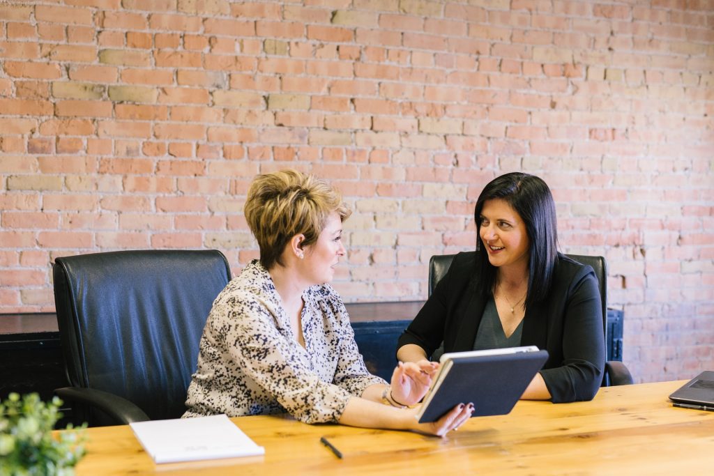 Two women at a conference table. You can practice your English speaking skills in one-on-one conversations.