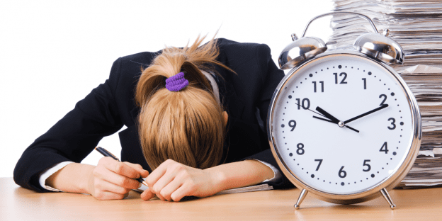 A woman asleep on a table by a clock that says it's after 10:00. She needs to change her ways.