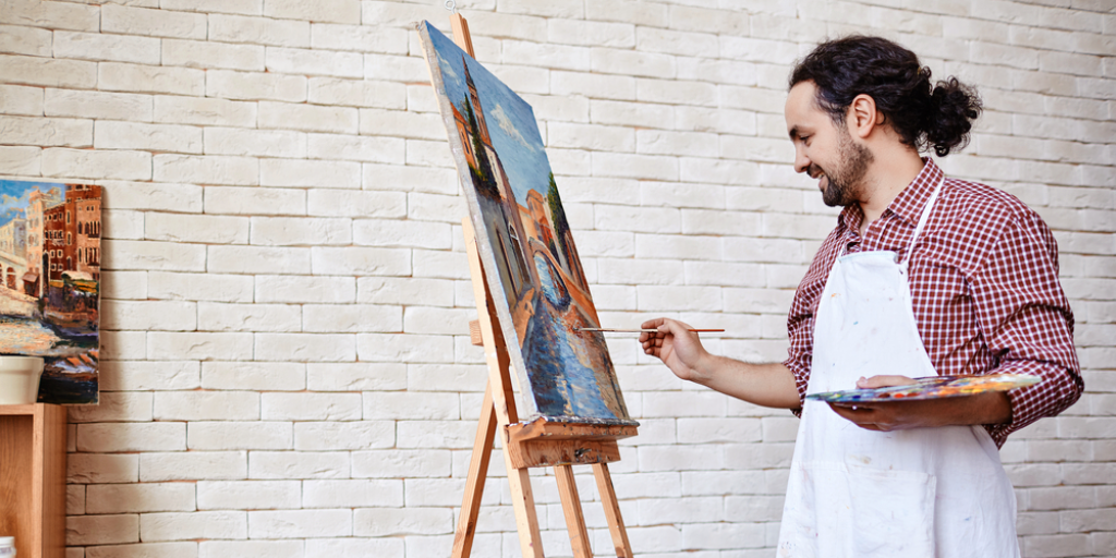 A man at an easel painting on a canvas