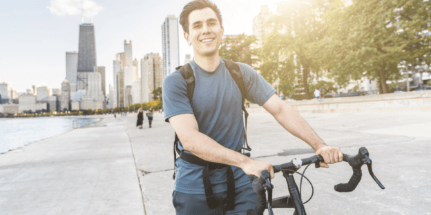 A man with a bicycle with the Chicago skyline in the background