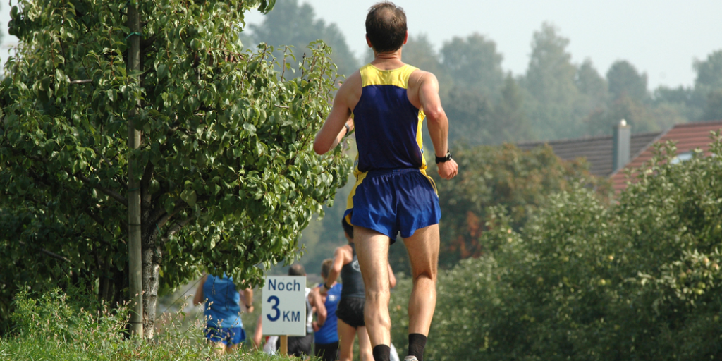 A runner in the woods has fallen behind the others in the race.