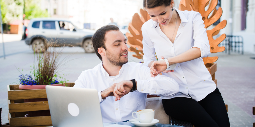 Two people looking at their watches in a café