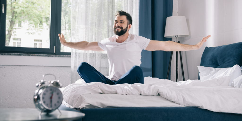 A man doing stretches on his bed in the morning.