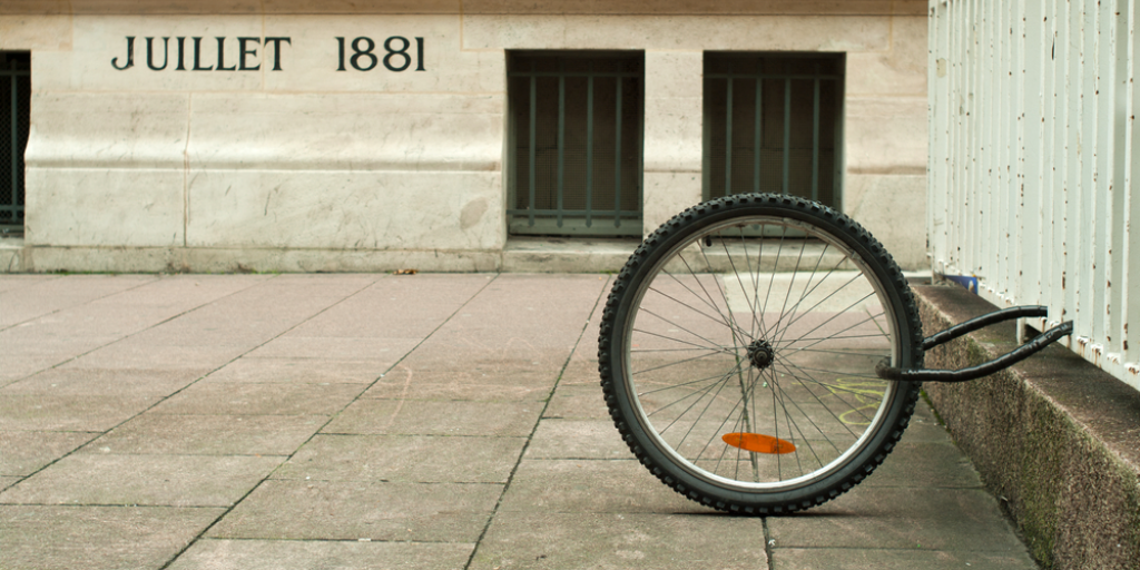 A single bicycle wheel locked to a fence