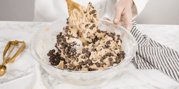 Chocolate chips are mixed into cookie dough.