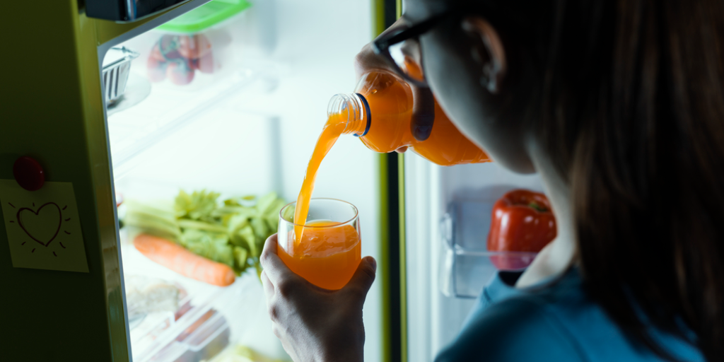 A woman pours orange juice at night