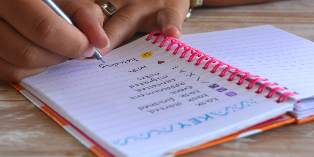 A woman is using a handwritten journal to plan ahead.