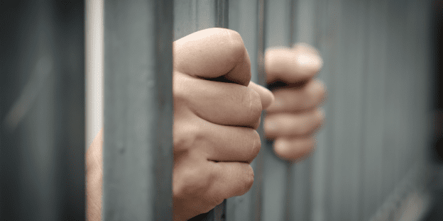 The hand of a person is visible in a jail.