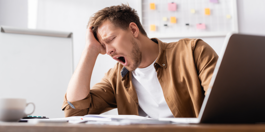 A man yawning at his desk