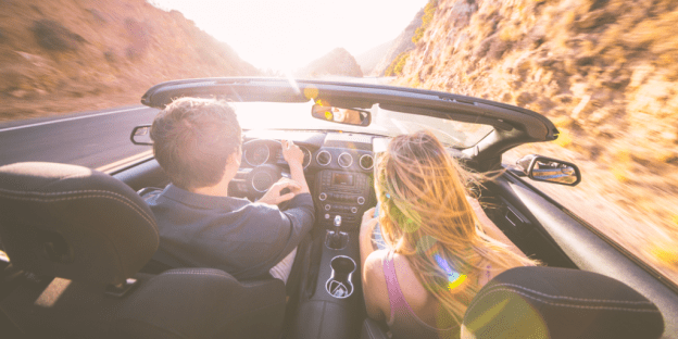 A couple in a convertible set off on a long road trip.