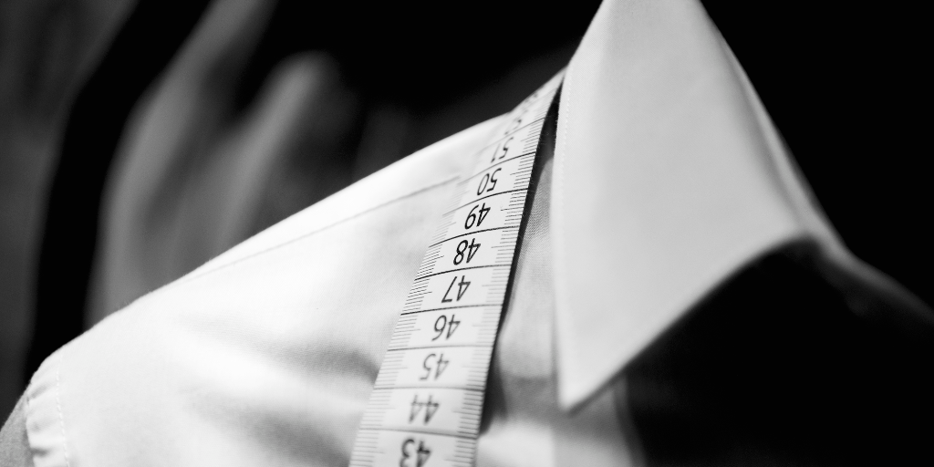 A tailor's measuring tape over a men's shirt on a mannequin.