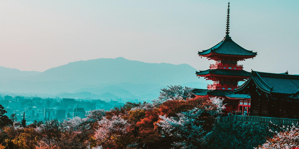 A view of a Japanese pagoda with mountains in the distance on a clear day
