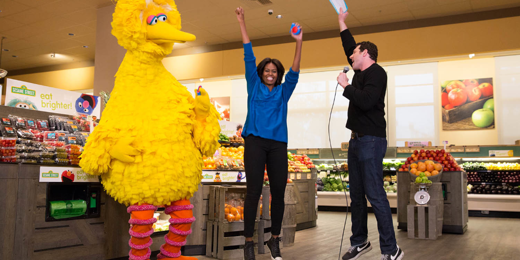 Big Bird is shown with Michelle Obama and another man in a grocery store