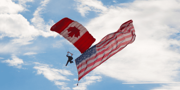 A man jumps from a plane amid unfurled flags of the United States and Canada