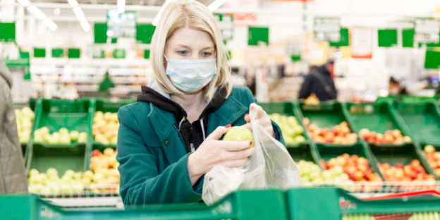 A woman wearing a paper face mask at the grocery store.