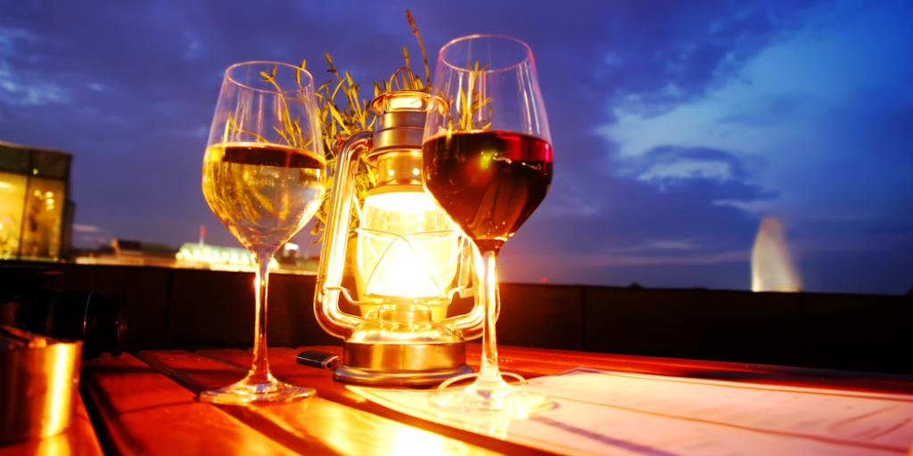 A glass of red and white wine besides a lantern