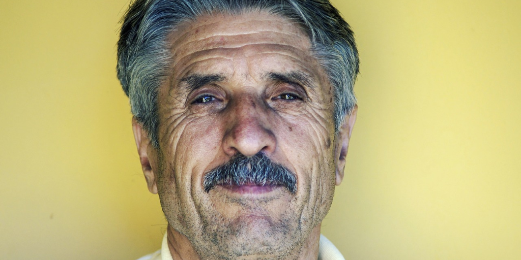 A man with a bushy mustache on a yellow background