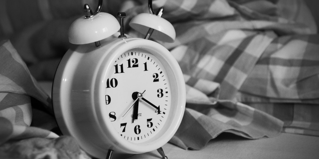 A black and white photo of a white alarm clock