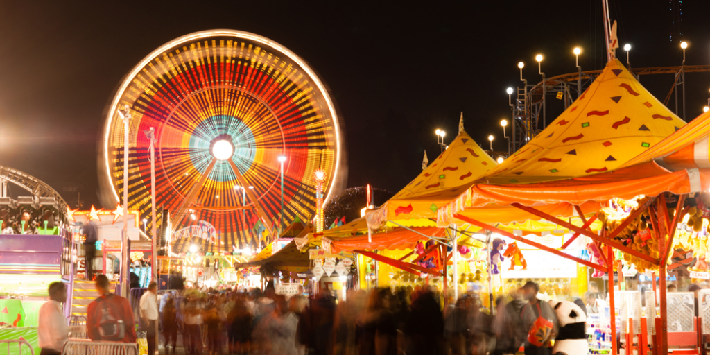 Carnival games and rides at a state fair at night