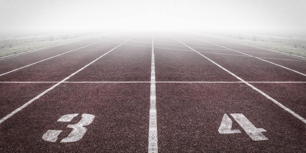 The third and fourth lanes of a maroon-colored running track on a foggy day