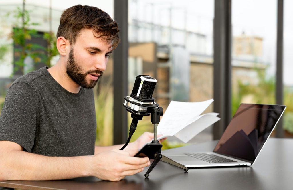 A man at a microphone. You can practice your English speaking skills alone, for example by memorizing lines from a movie. 