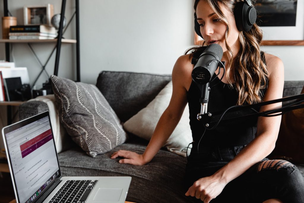 A woman recording a podcast in her living room. Several English learning podcasts aim to help you improve your listening skills.